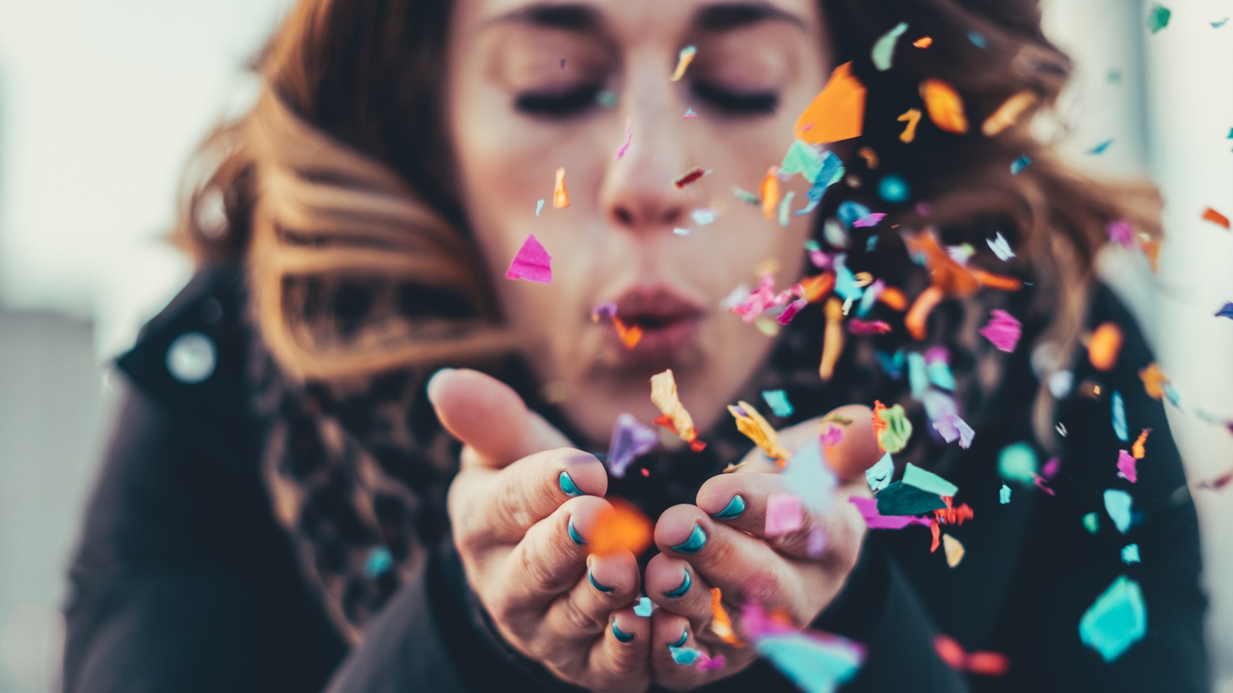 woman blowing confetti out of hands